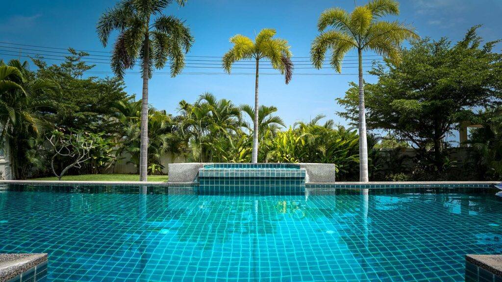 Beautiful photo of a swimming pool facing 3 palm trees.